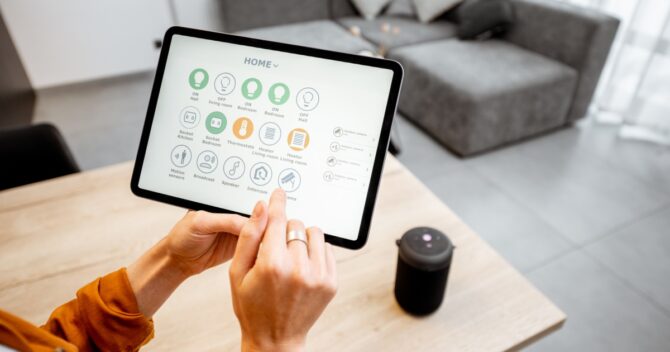 Woman controlling smart devices with a digital tablet at home
